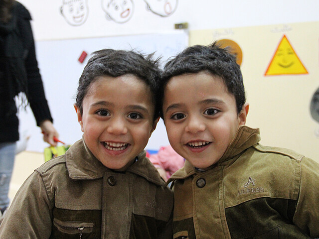 Zwillinge in Jordanien lächeln in die Kamera.