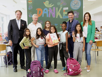 Gleiche Bildungschancen für alle Kinder: Die Privatstiftung Kärntner Sparkasse unterstützt unsere Schulstarthilfe. Kinder und Erwachsene vor einer Tafel mit „DANKE“ bei Spendenübergabe im Caritas-Lerncafe.