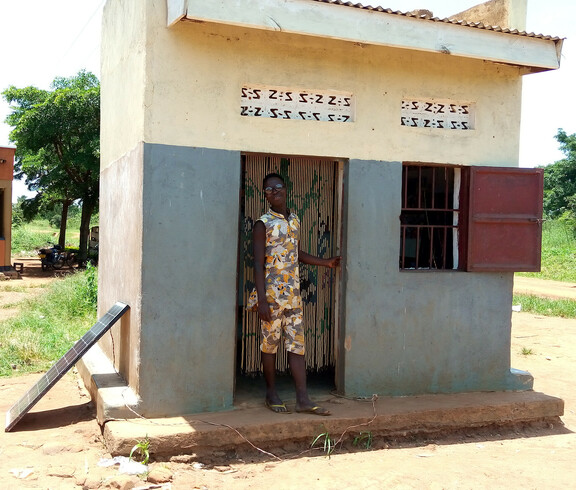 Ein junger Mann steht im Eingang seines eigenen kleinen Barber-Shops in Uganda.