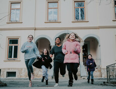 Kinder und Jugendliche unserer sozialpädagogischen Einrichtung, das Haus Antonius in Treffen, laufen aus dem Eingang des Hauses.