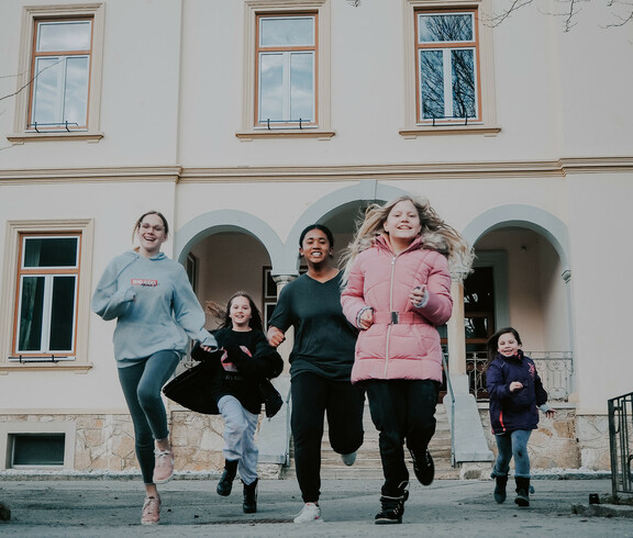 Kinder und Jugendliche unserer sozialpädagogischen Einrichtung, das Haus Antonius in Treffen, laufen aus dem Eingang des Hauses.