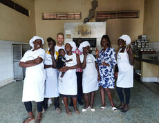 Das Team der neuen Bäckerei in Moroto steht stolz vor dem Ofen der Bäckerei und lächelt in die Kamera.