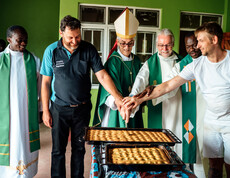 Der jetzige Bischof von Kärnten Josef Marketz und ein Bischof aus Uganda schneiden mit Projektförder*innen den ersten Kuchen der Bäckerei an.