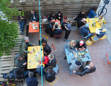 Im Gastgarten des magdas LOKAL stehen bunte Tische, über die eine Lichterkette hngt. Alle Tische sind besetzt.