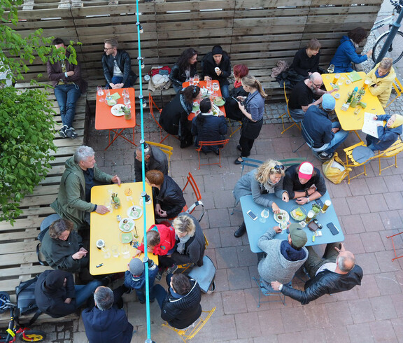 Im Gastgarten des magdas LOKAL stehen bunte Tische, über die eine Lichterkette hngt. Alle Tische sind besetzt.